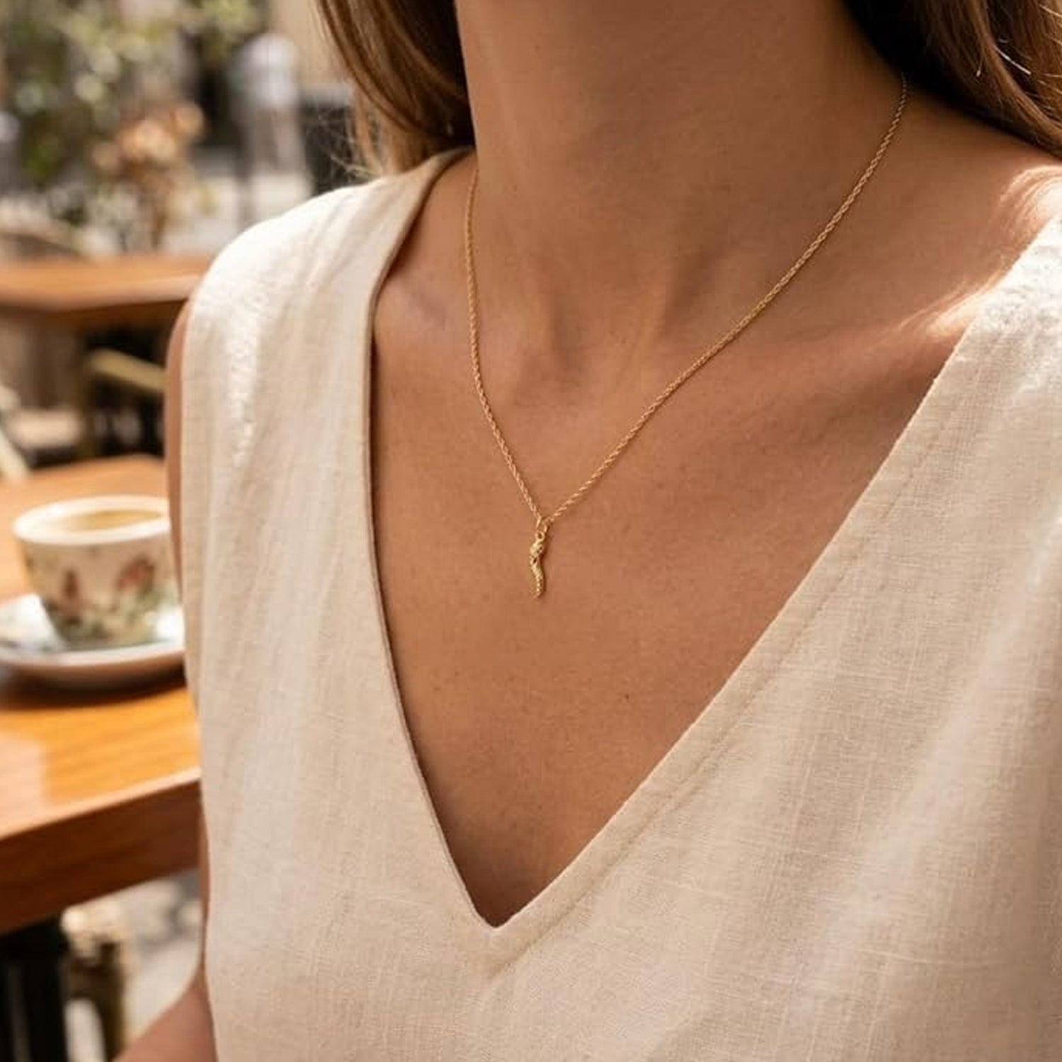 Person wearing a gold diamond cut italian horn charm with gold chain 
